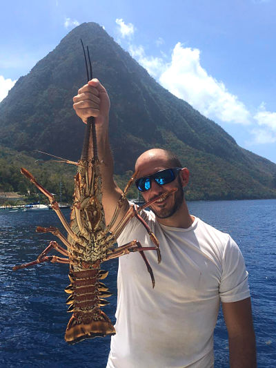 Nuestro capitán Carlos sujetando una enorme langosta en nuestro viaje por el Caribe en Catamaran desde España